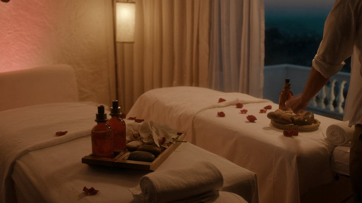 Sala de masaje para parejas con dos camillas, aceites y pétalos de rosa